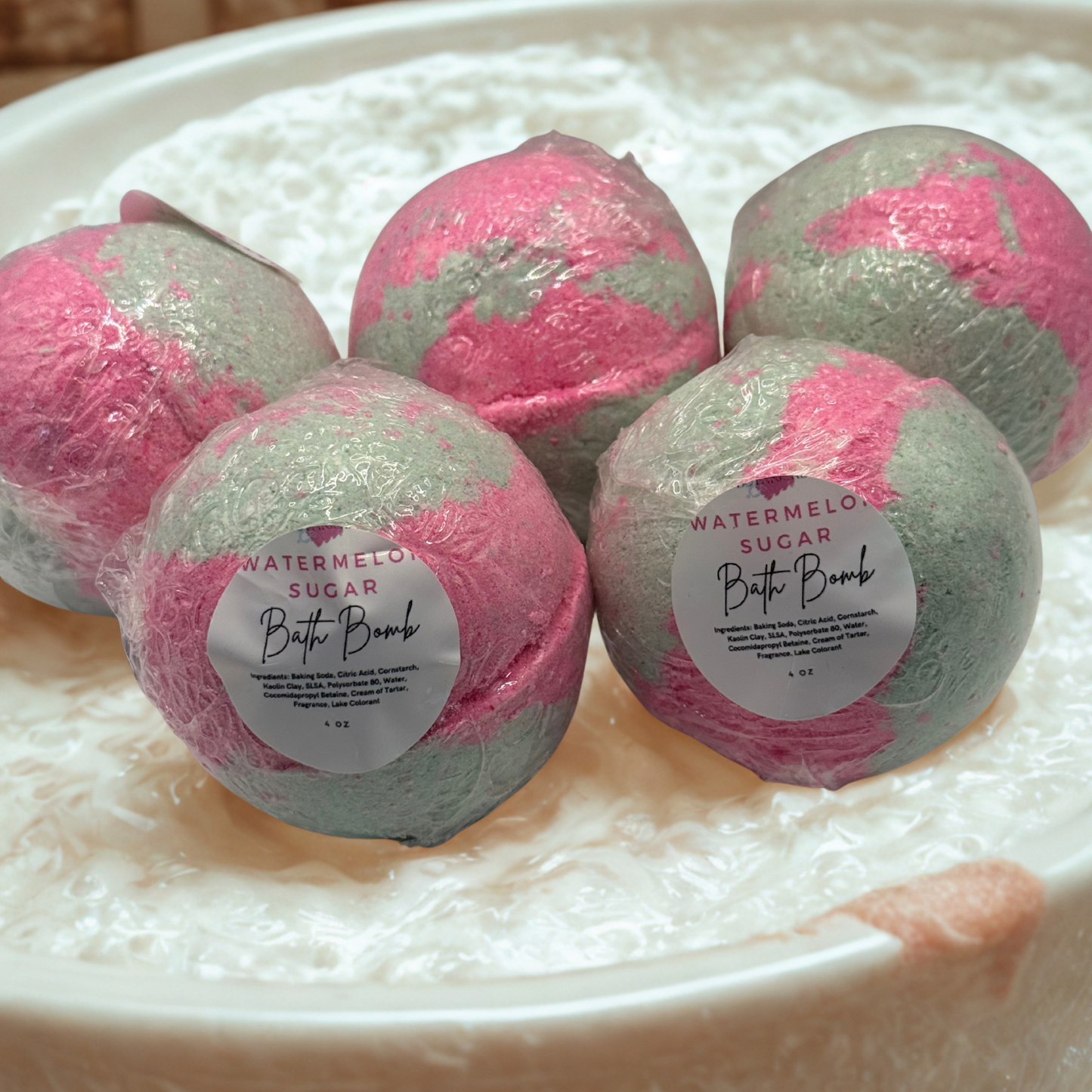 Pink and green bath bombs with labels on a white surface