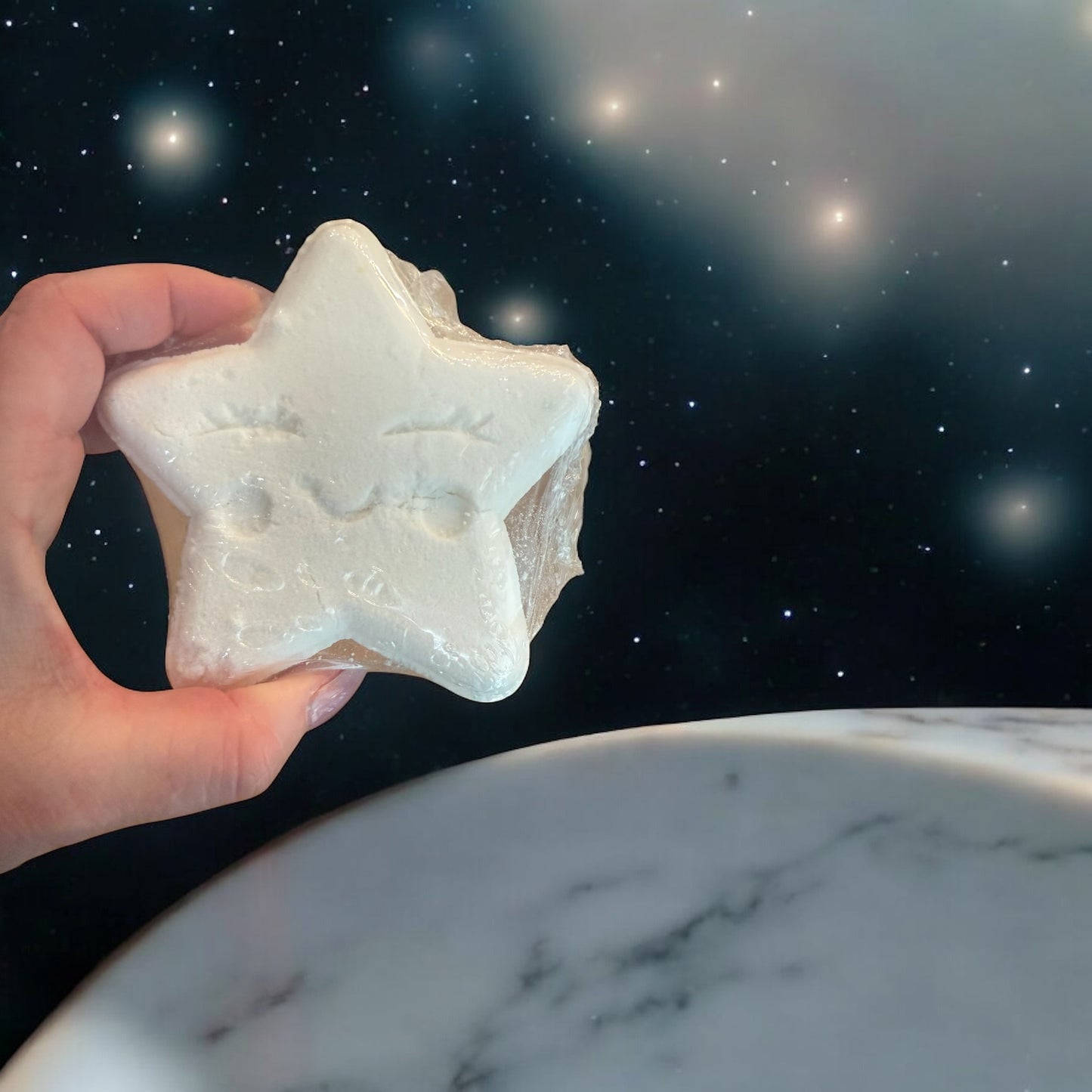 Star-shaped object held by a hand with a marble surface and starry night sky background