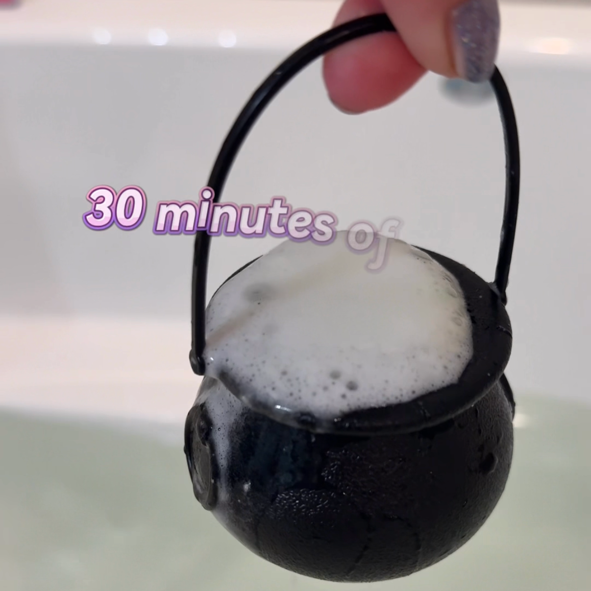 Black cauldron with soapy water held by a hand, with text overlay on a smartphone screen.