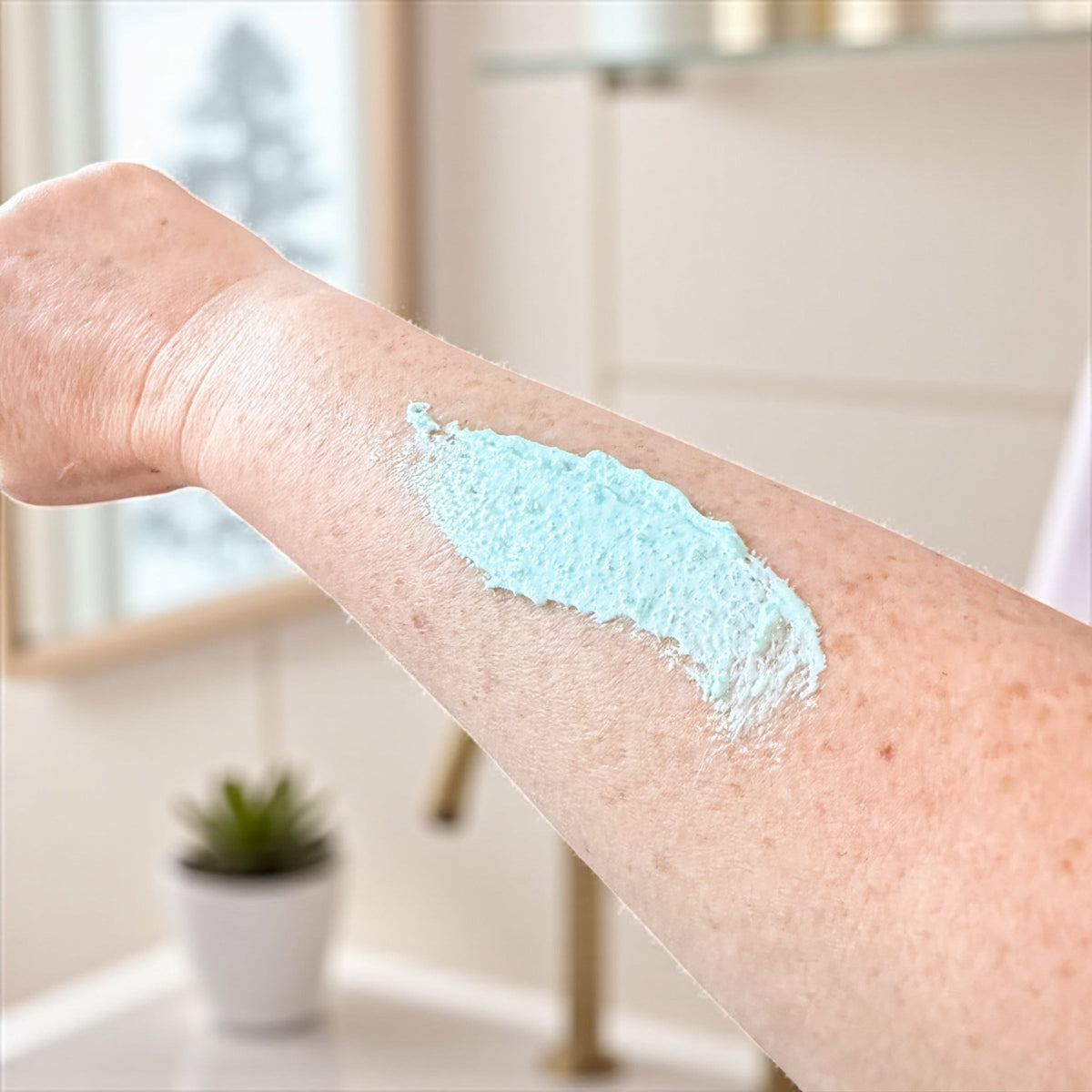 Person's arm with mint & menthol foot scrub application in a bathroom setting