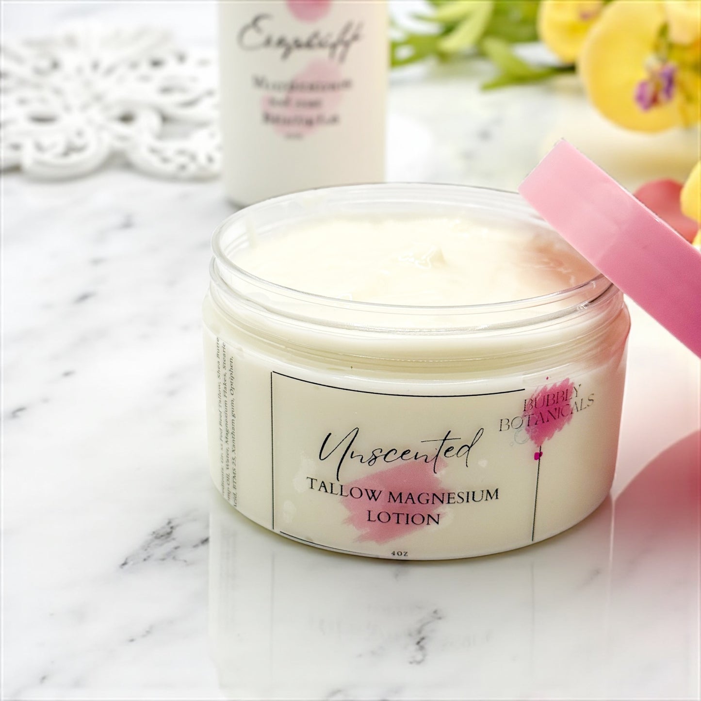 Jar of unscented tallow magnesium lotion with a pink applicator on a marble surface.
