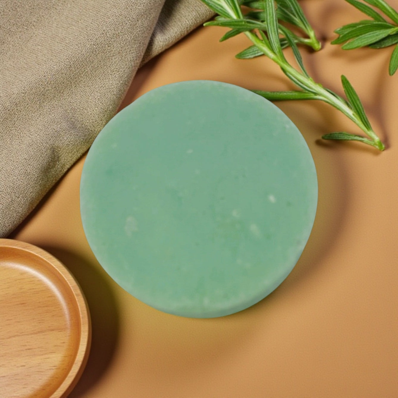 Green soap bar on a brown surface with a wooden dish and green leaves.