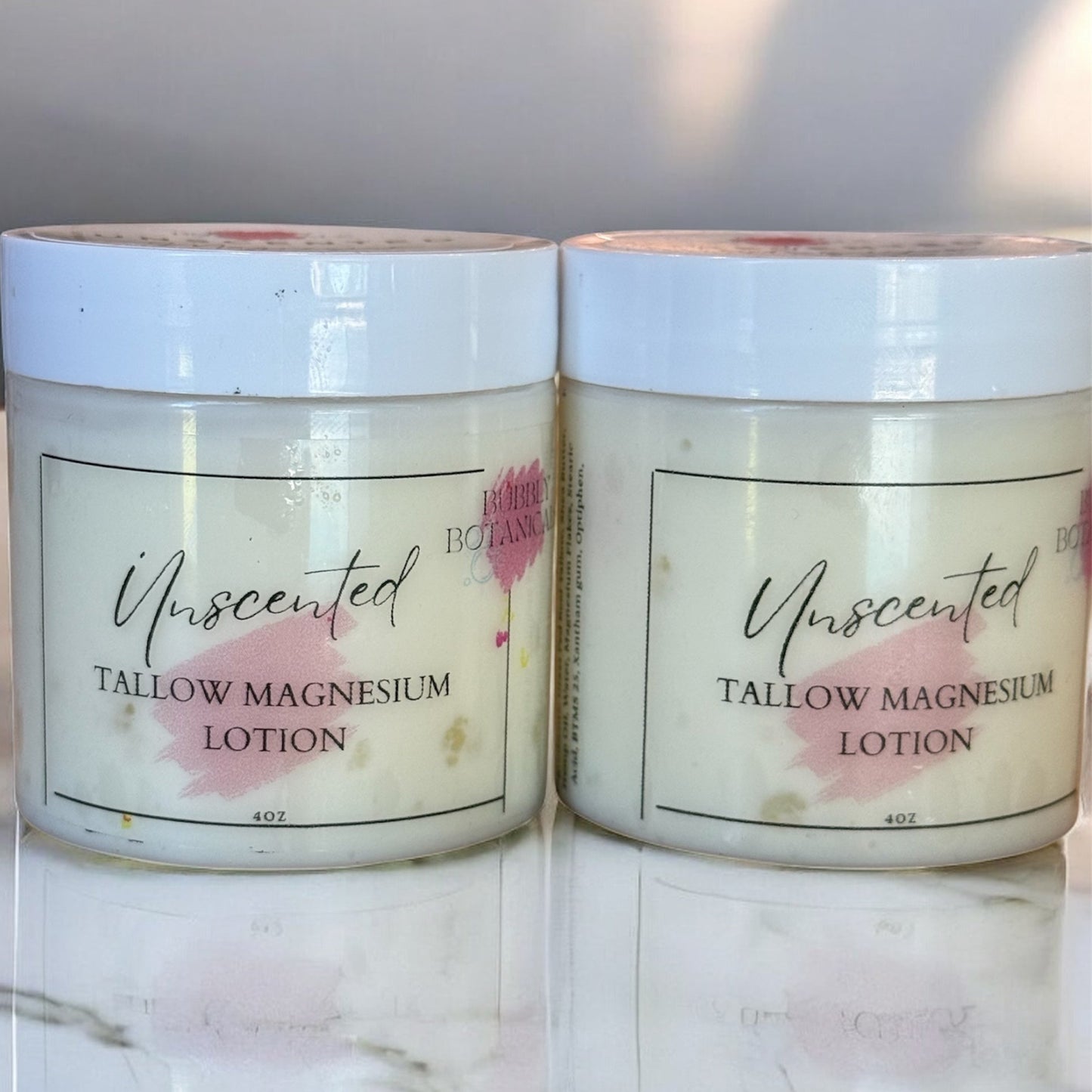 Two containers of unscented tallow magnesium lotion on a marble surface.