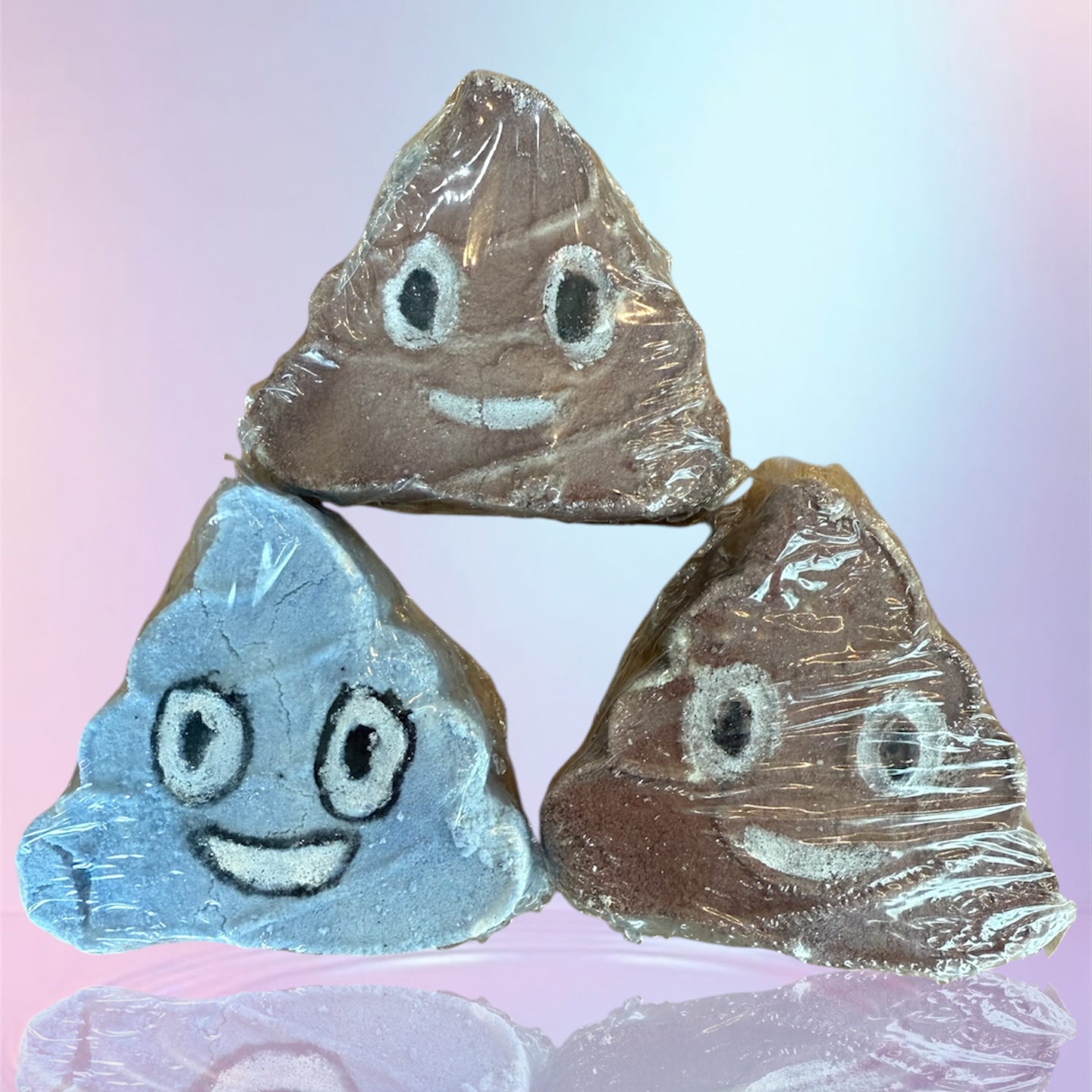 Three triangular rocks with facial expressions on a reflective surface