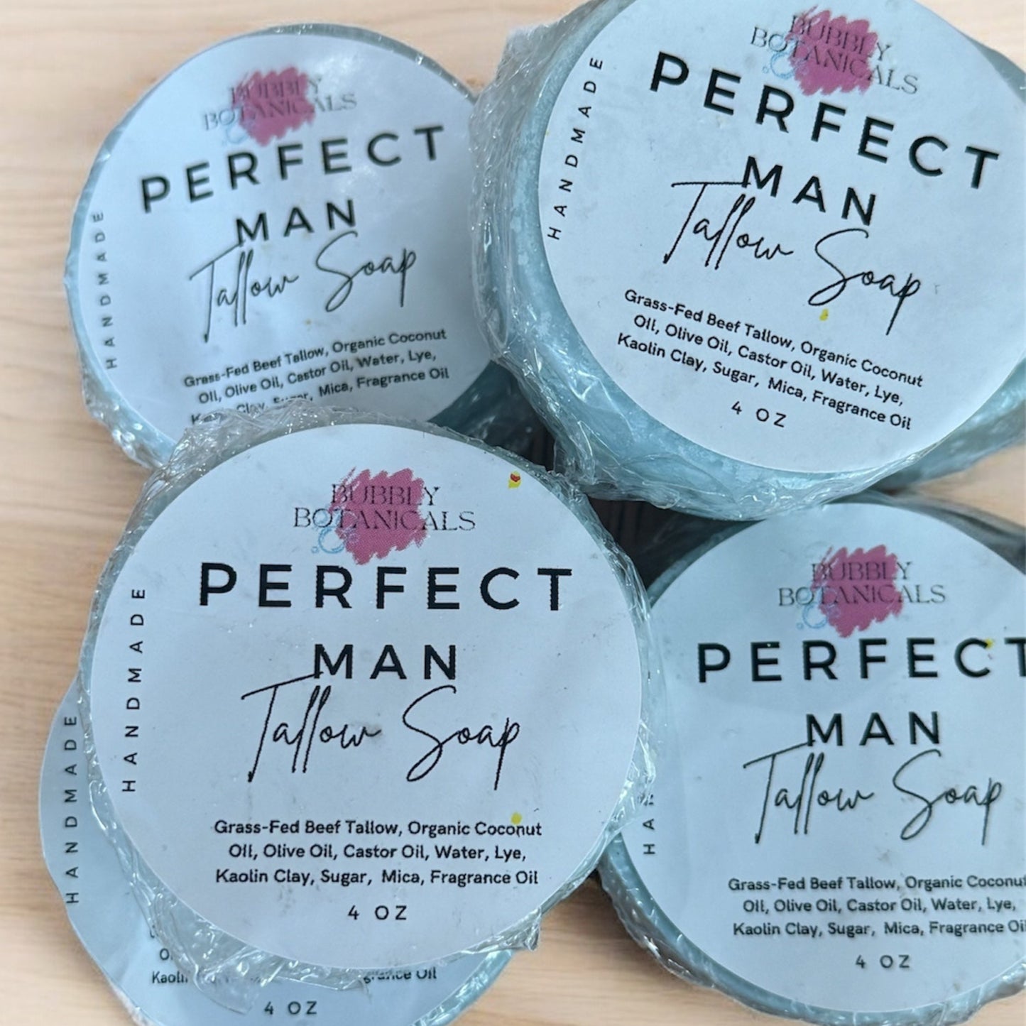 Four containers of 'Perfect Man' tallow soap on a wooden surface
