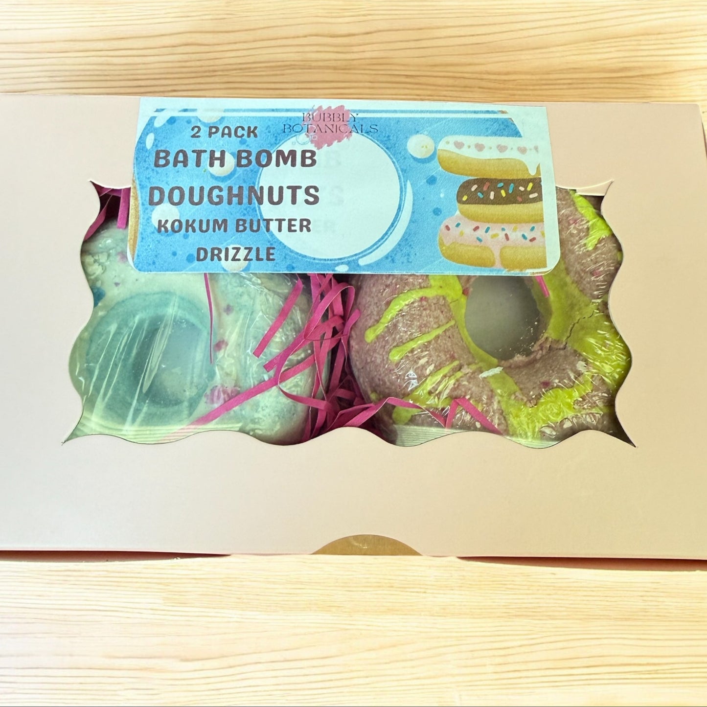 Bath bomb doughnuts in a box with a label on a wooden surface