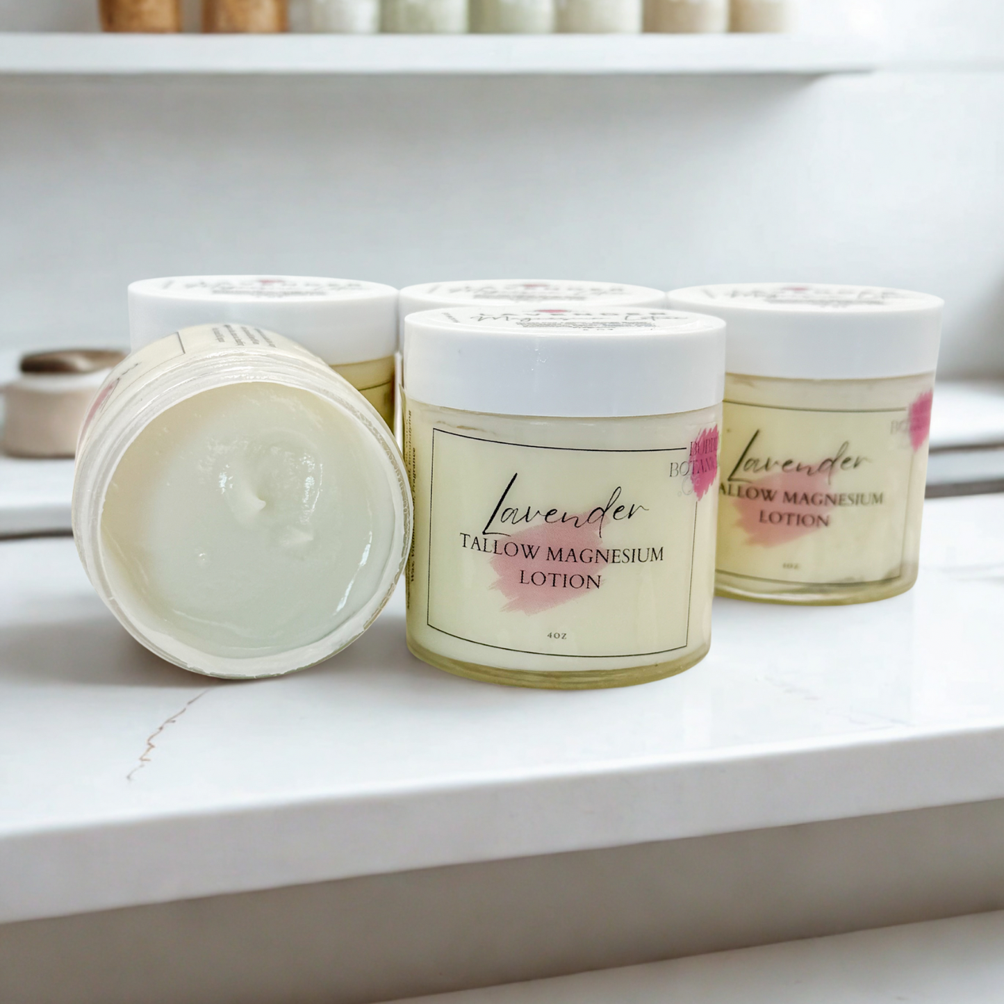 Lavender tallow magnesium lotion jars on a white surface with shelves in the background.