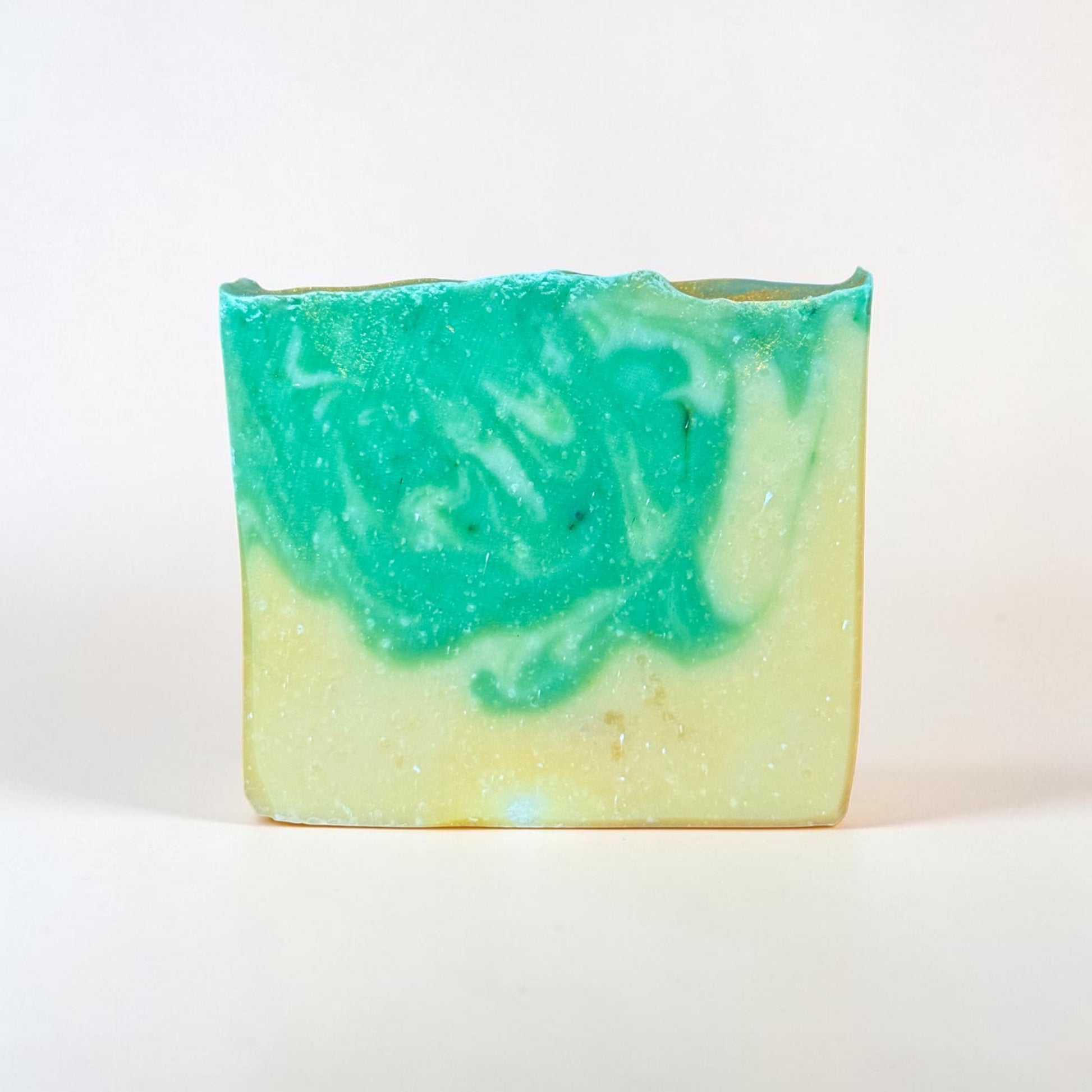 Handmade bamboo coconut tallow soap bar by Bubbly Botanicals with green swirl design and natural bamboo and coconut props on a clean white background and no label