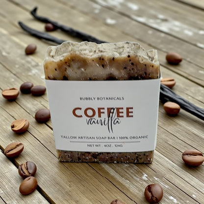 Coffee vanilla tallow soap bar with packaging on a wooden surface with coffee beans and vanilla beans.
