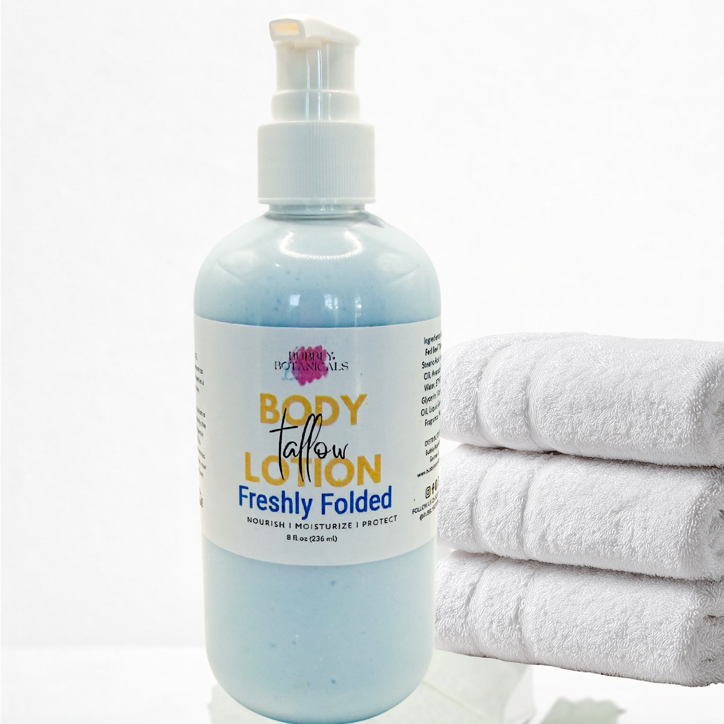 Body lotion bottle labeled 'Freshly Folded' with a stack of white towels on a white background