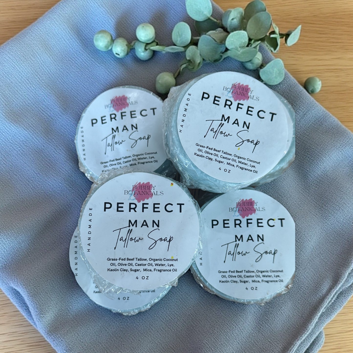 The perfect man mini tallow soap on a cloth on a wooden table with some eucalyptus sprigs nearby