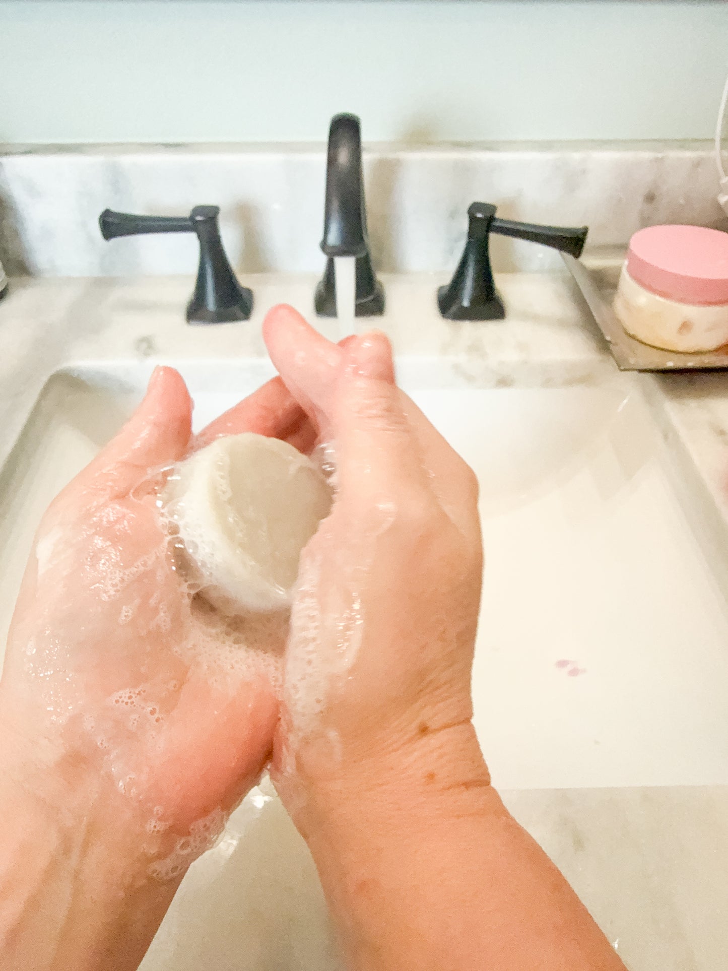 Mini soap being held near a sink with a lather