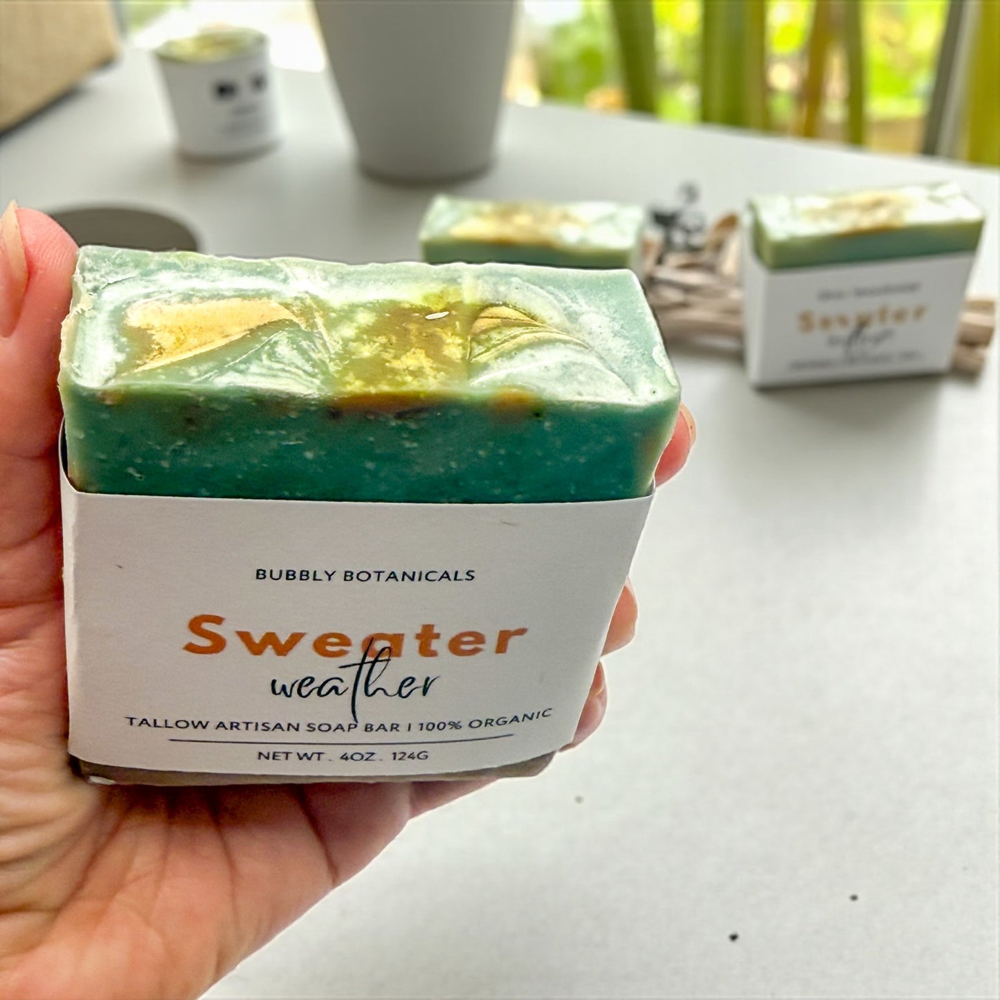 Sweater weather tallow soap swirl top with a background of a concrete table with other soaps on it