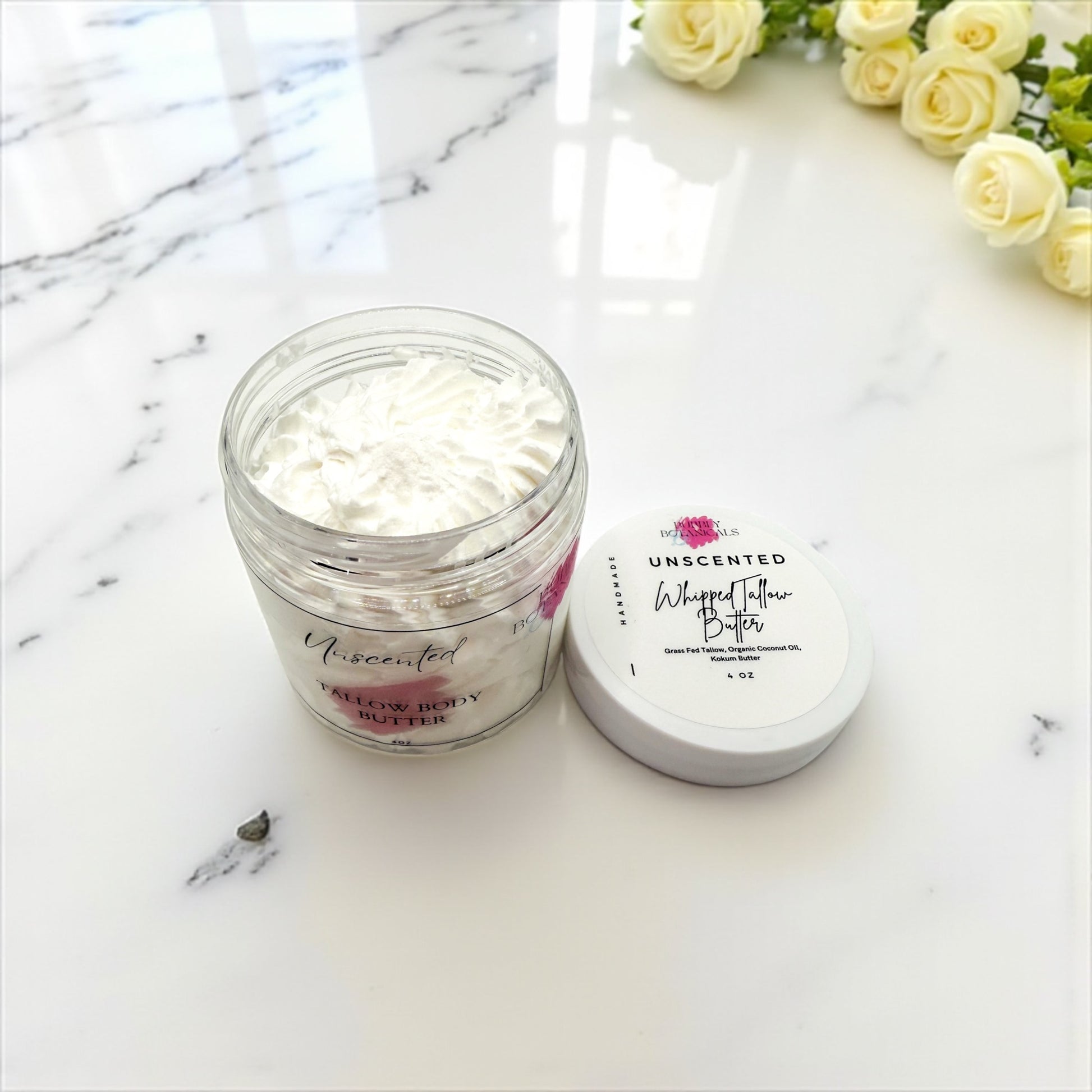 Jar of whipped butter on a marble surface with flowers in the background