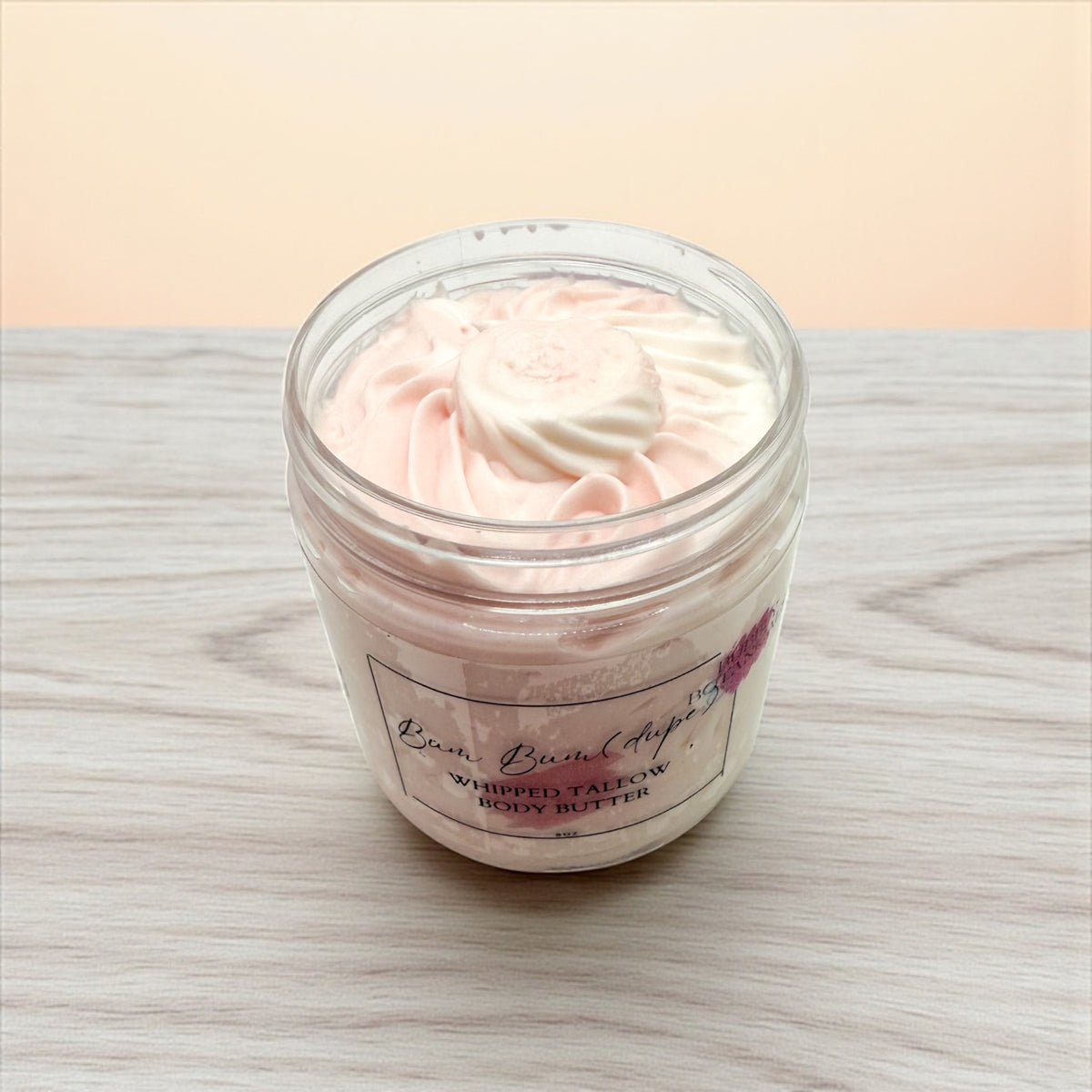 Jar of whipped body butter with a visible brand label on a wooden surface.