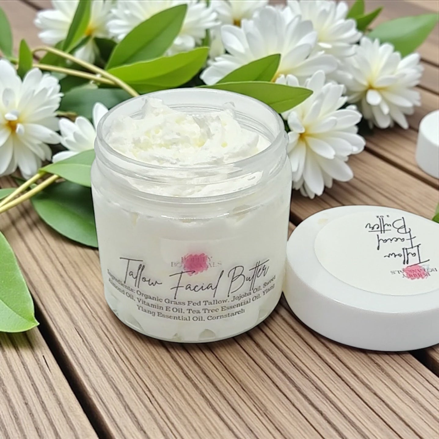 Jar of Tallow Facial Butter with flowers on a wooden surface
