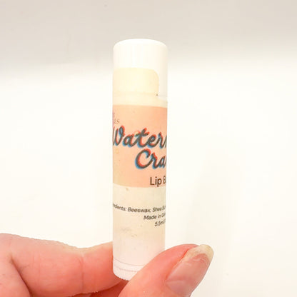 Lip balm stick held in a hand with a plain background