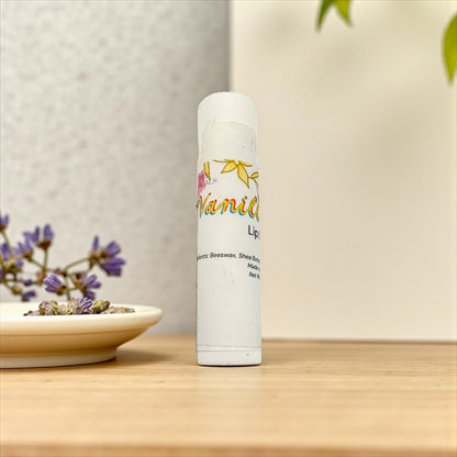 Lip balm tube with floral design on a wooden surface with a blurred background