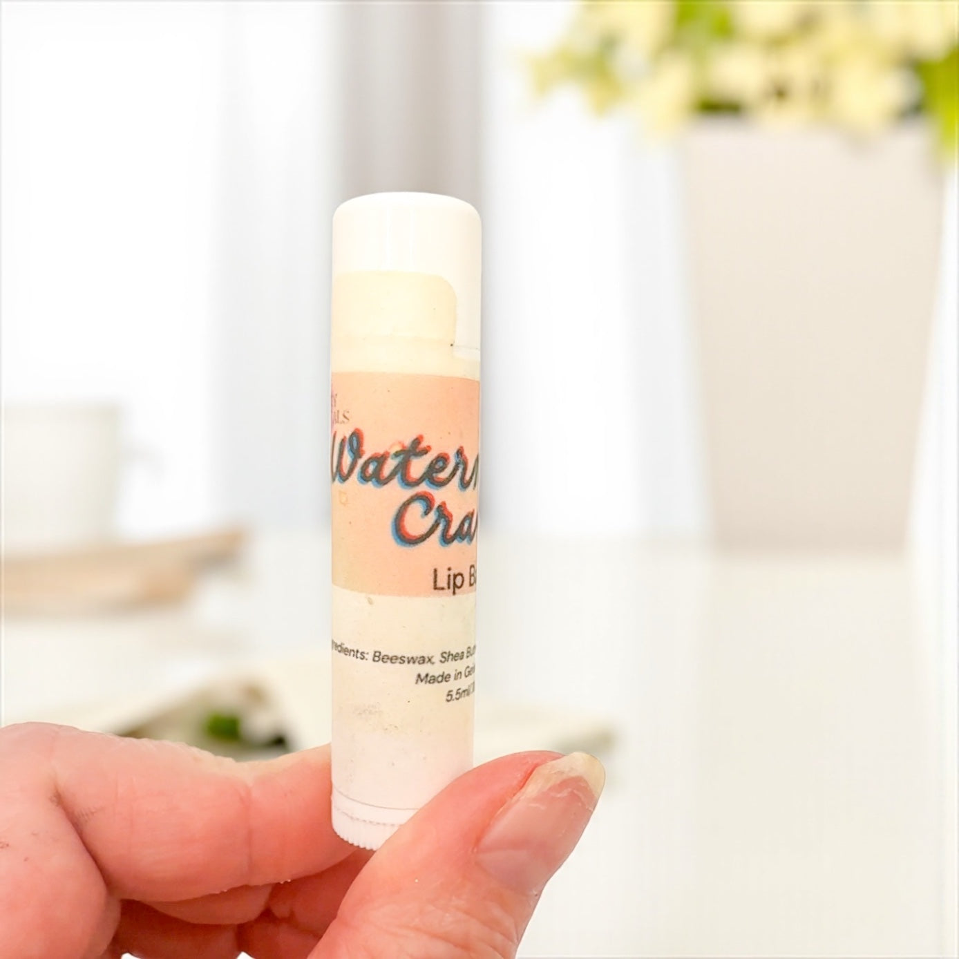 Lip balm stick held by a hand with a blurred background