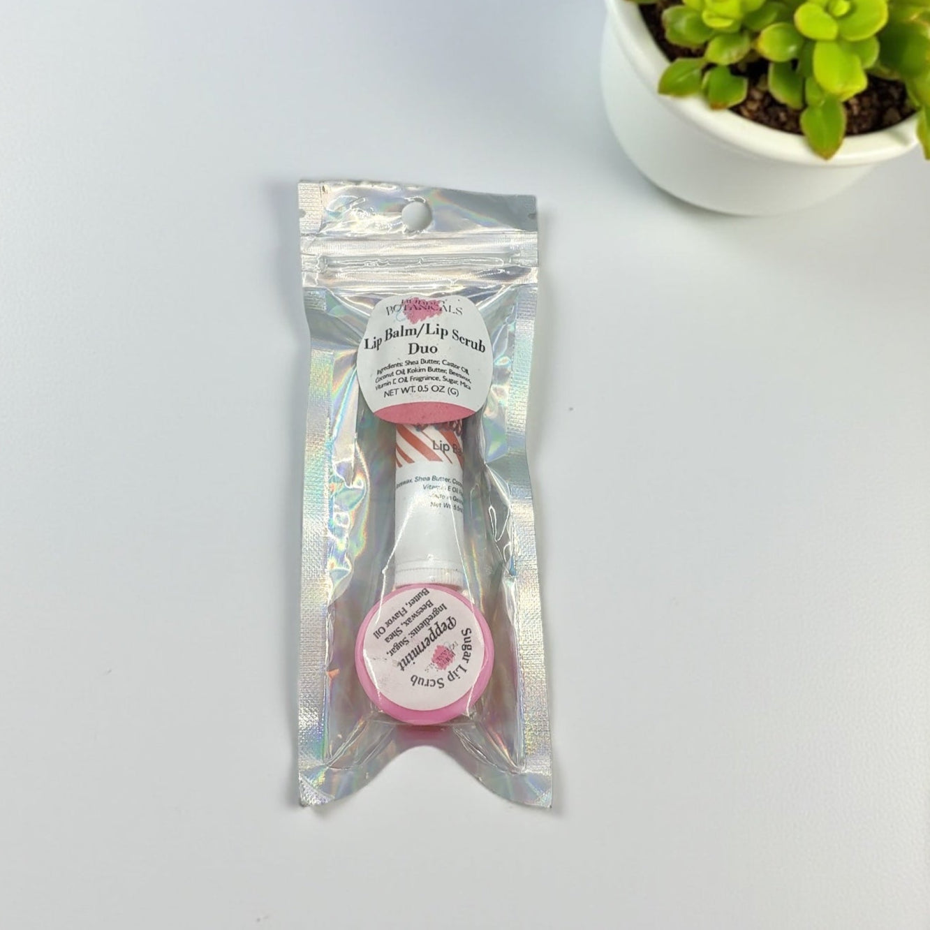 Packaged lip balm with a small plant in the background on a light gray surface