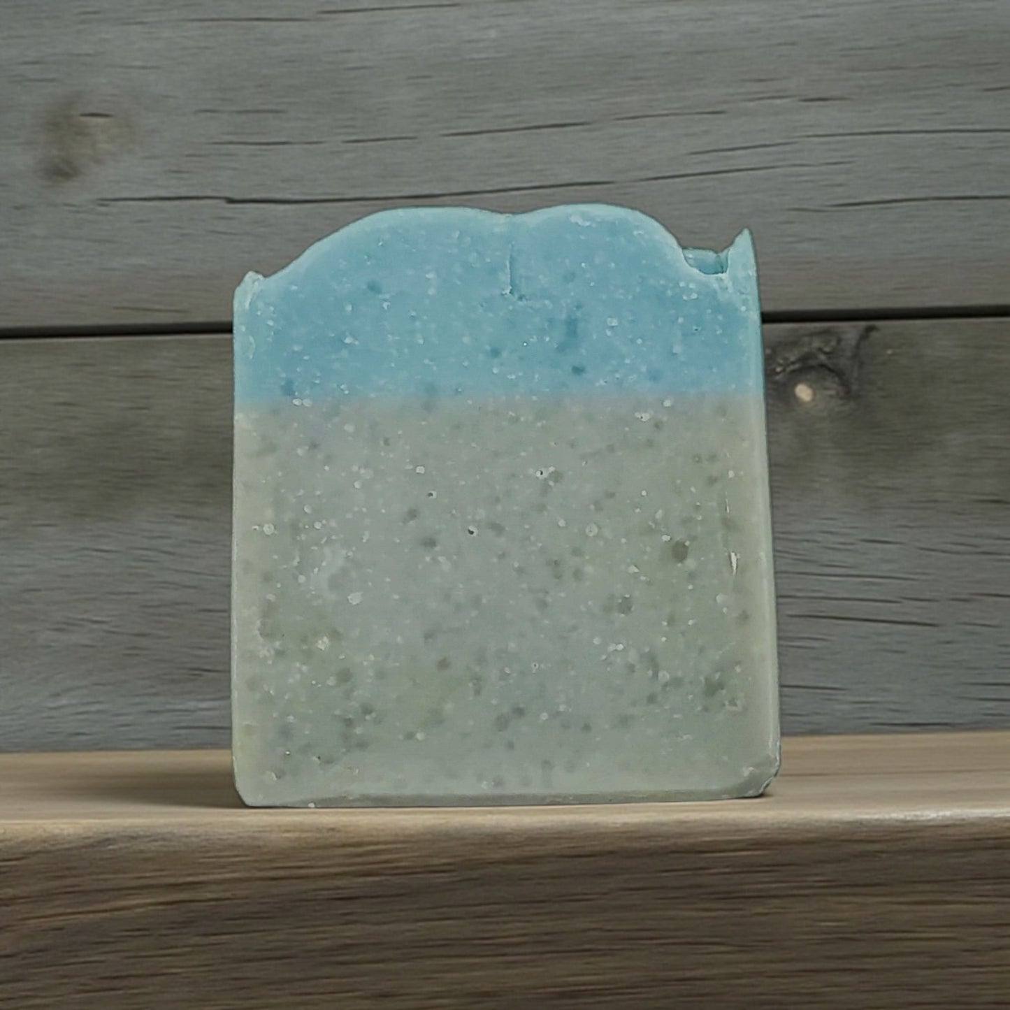 Blue and green soap bar on a wooden surface with a wooden background