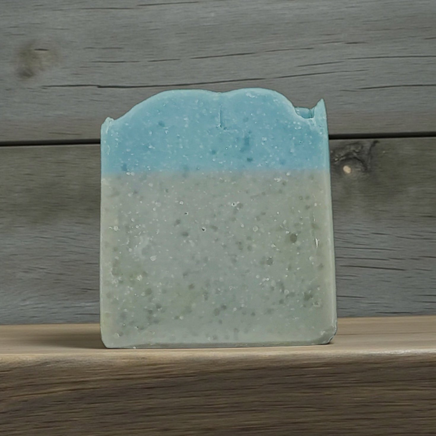 Blue and green soap bar on a wooden surface with a wooden background