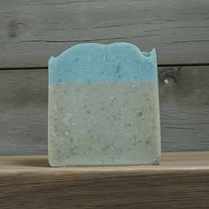 Blue and green soap bar on a wooden surface with a wooden background