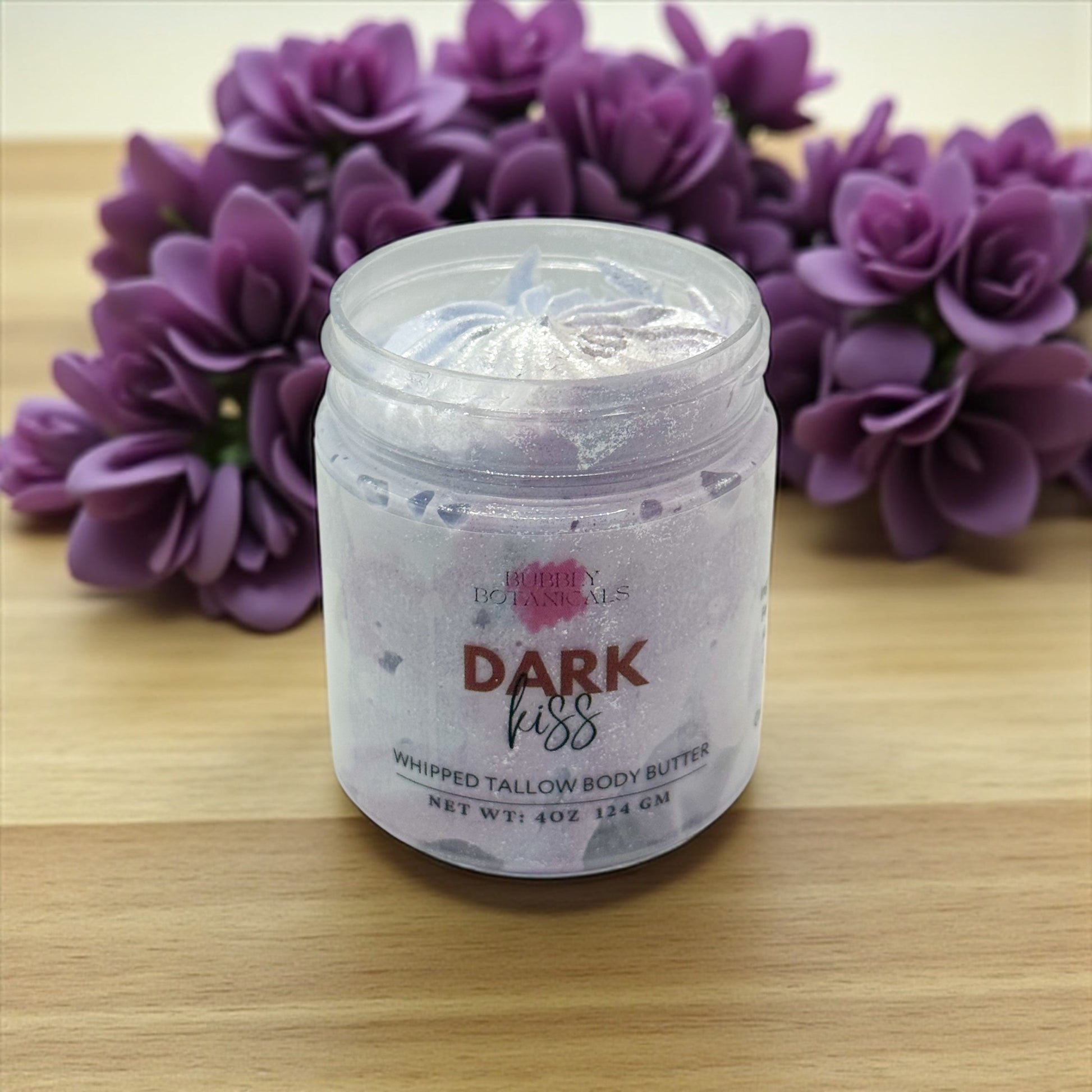 Jar of 'Dark Kiss' whipped tallow body butter with purple flowers in the background