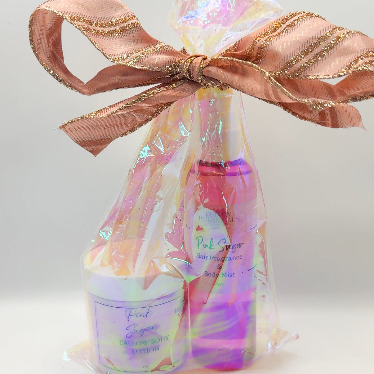 Bath and body set with a bottle and jar wrapped in colorful paper and a pink bow on a light background.