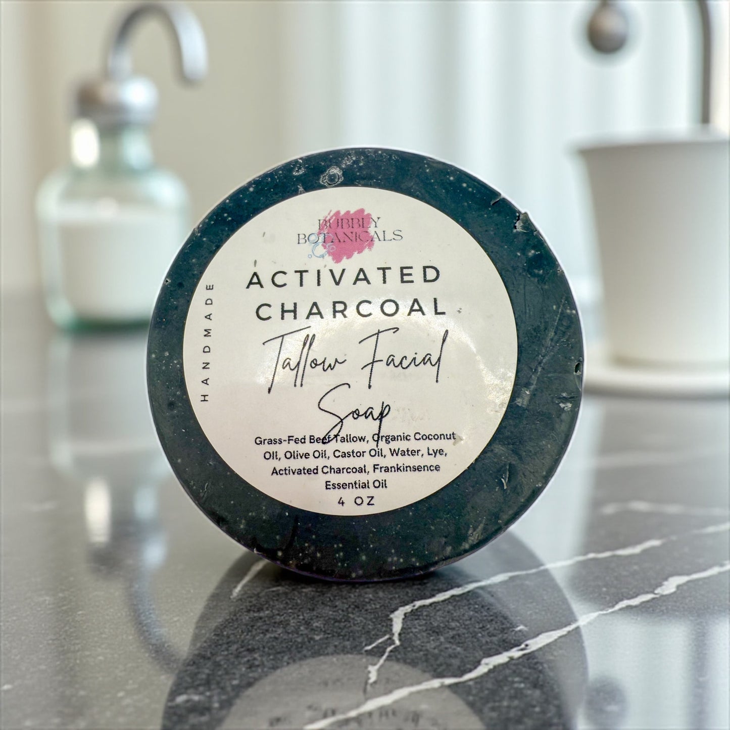 Activated charcoal facial soap on a marble surface with a blurred bathroom background