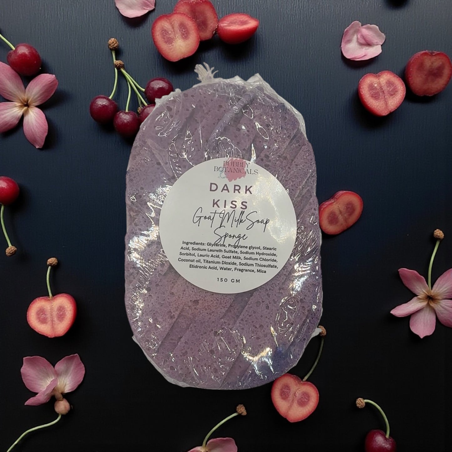Dark Kiss Grape Milk Soap Sponge with cherry and flower decorations on a dark background