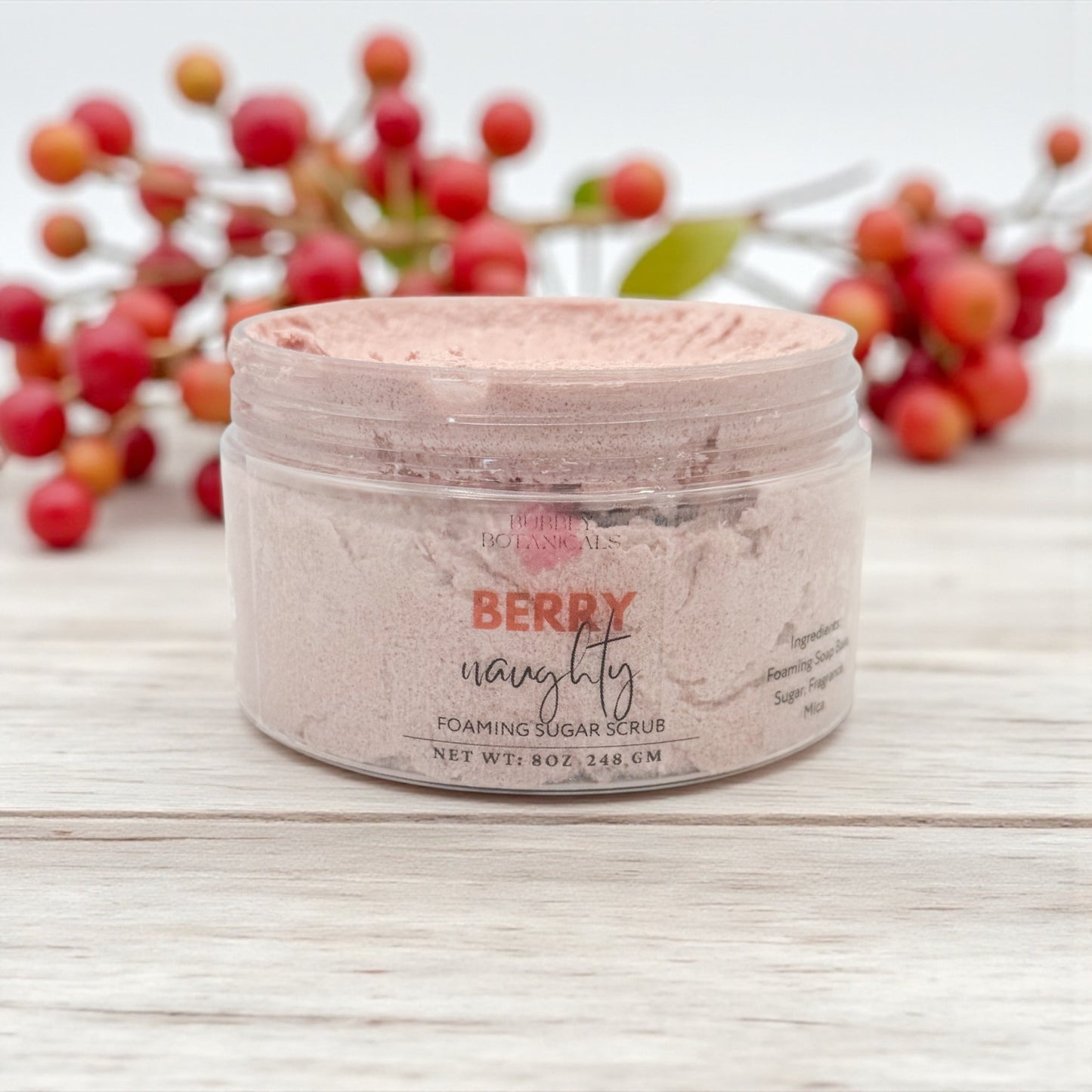 Jar of berry-themed foaming sugar scrub with berries in the background