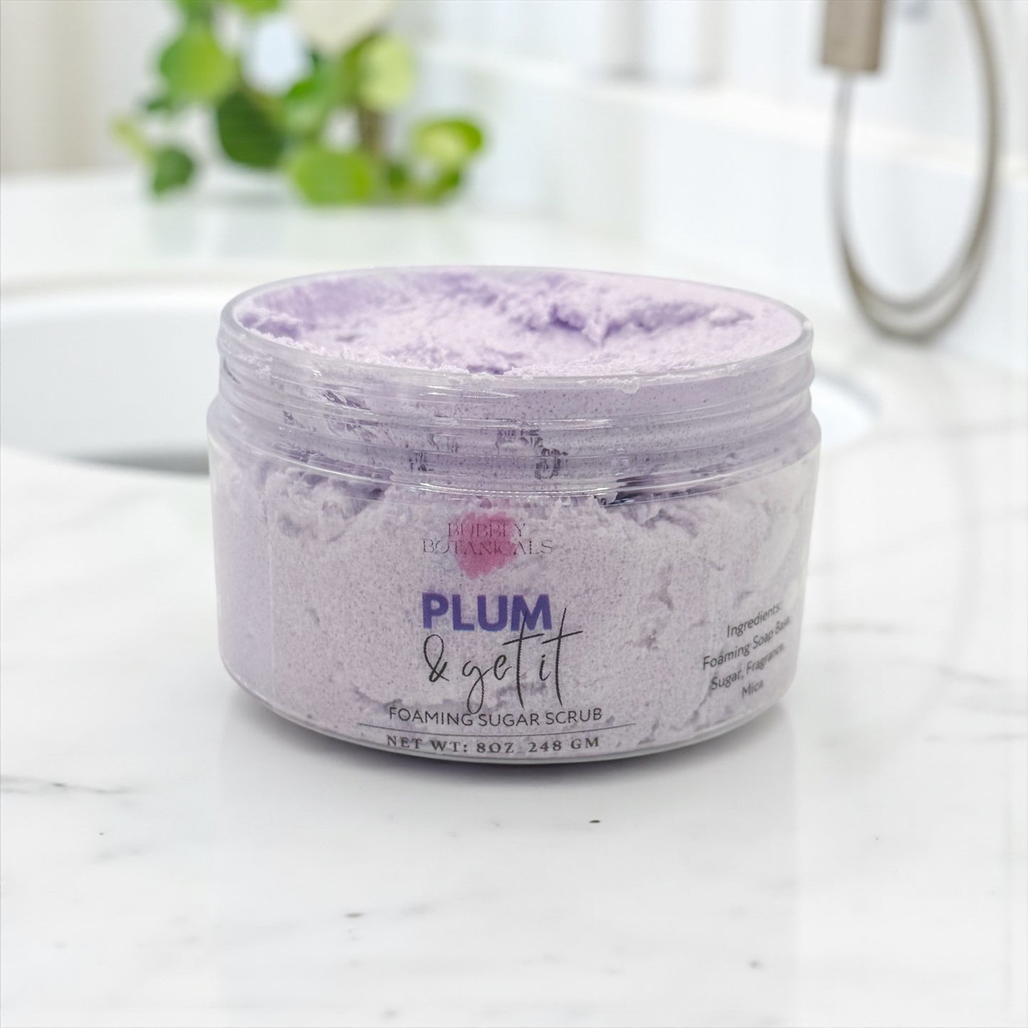 Jar of Plum & Get It foaming sugar scrub on a bathroom counter
