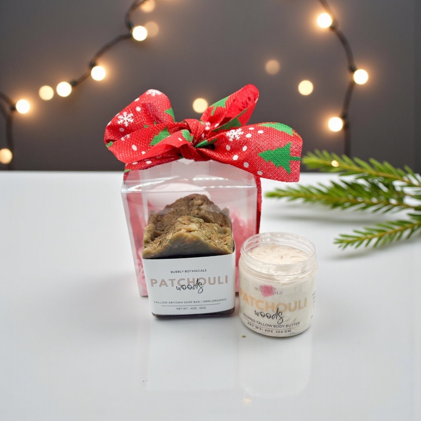 Candle and soap set with a decorative bow on a white surface with blurred lights in the background