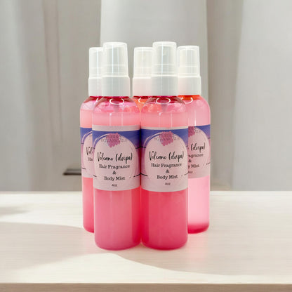 Three bottles of hair fragrance and body mist with pink and purple gradient on a white surface.