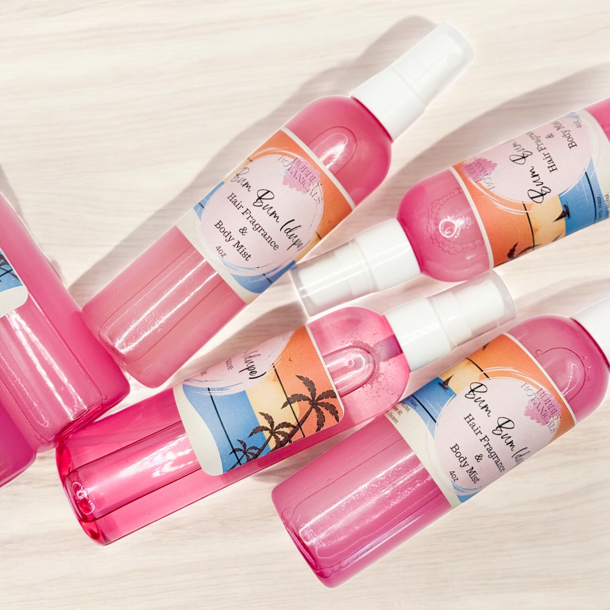 Set of pink hair balm and body mist bottles with colorful labels on a light background
