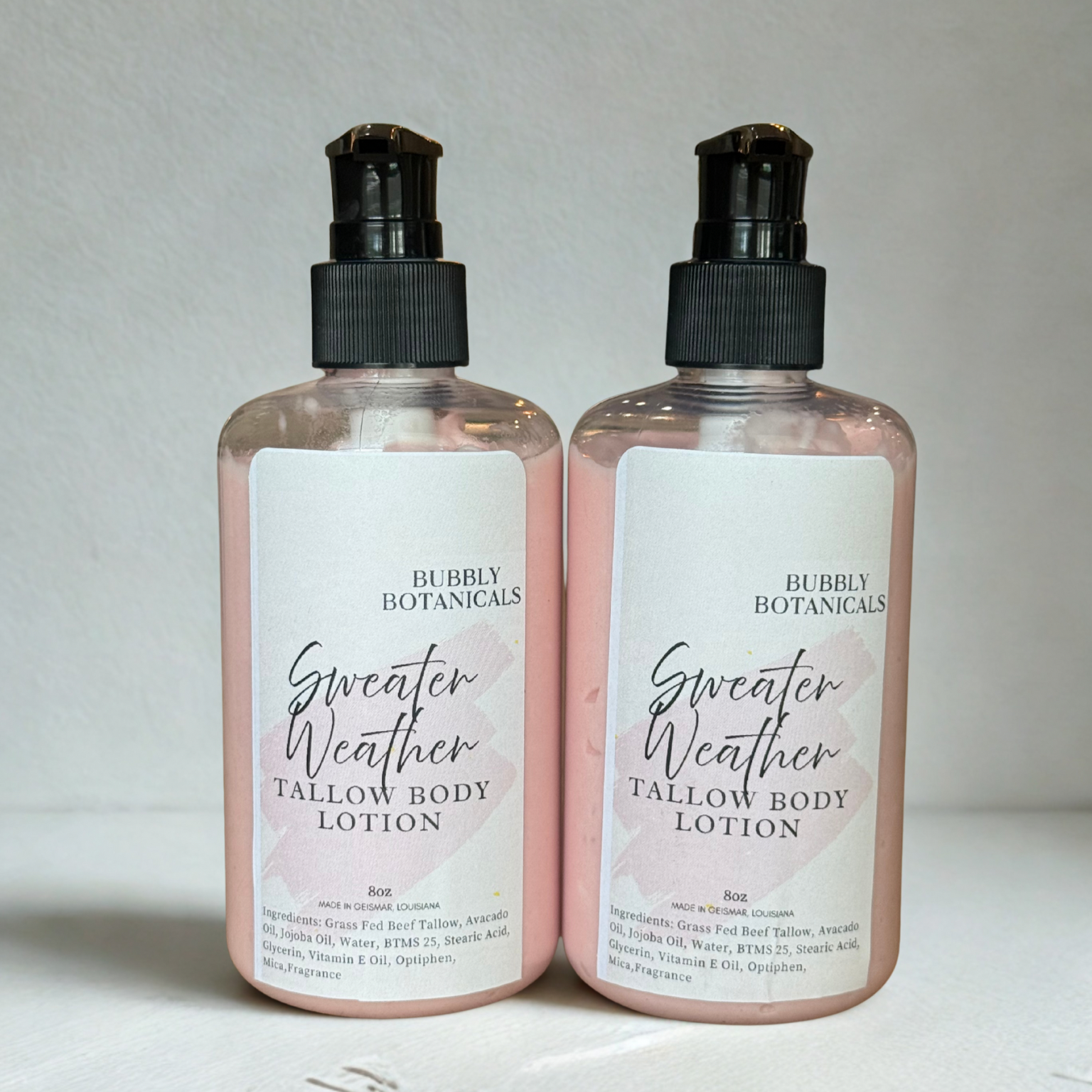 Two bottles of Bubly Botanicals Sweater Weather Tallow Body Lotion on a light background