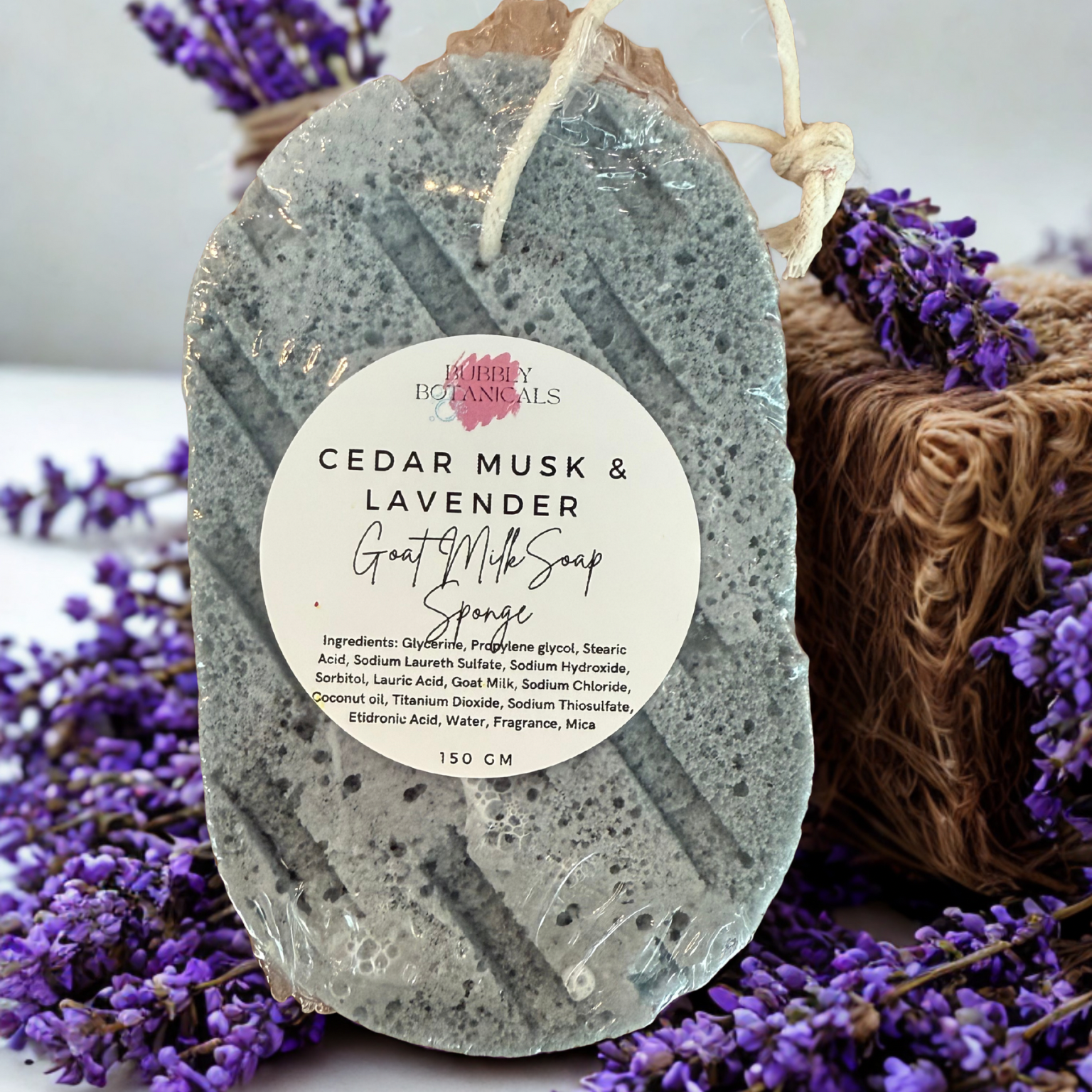 Cedar Musk & Lavender soap bar with a label, surrounded by lavender flowers on a white background