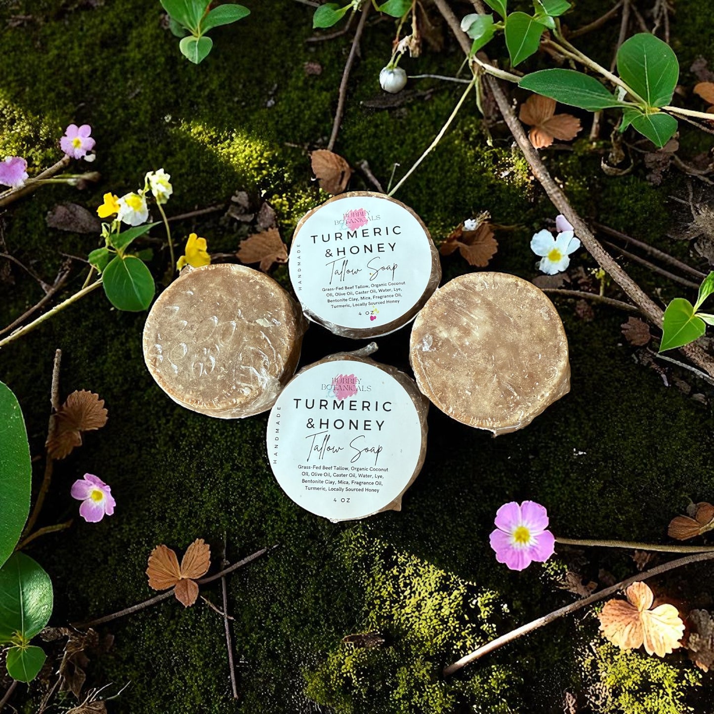 Turmeric & honey tallow mini soaps on a forest floor with flowers 