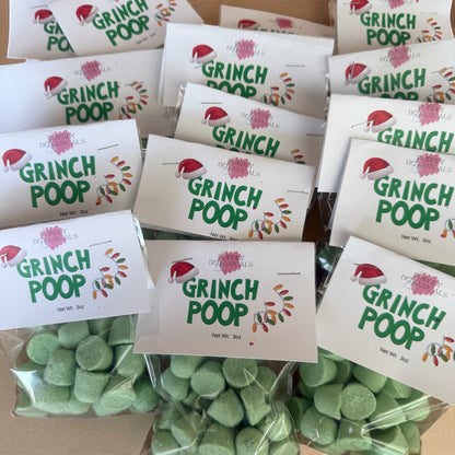 Green candy labeled 'Grinch Poop' with packaging on a cardboard surface.