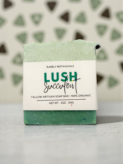 Green soap bar with a white label on a gray surface, against a patterned wall.