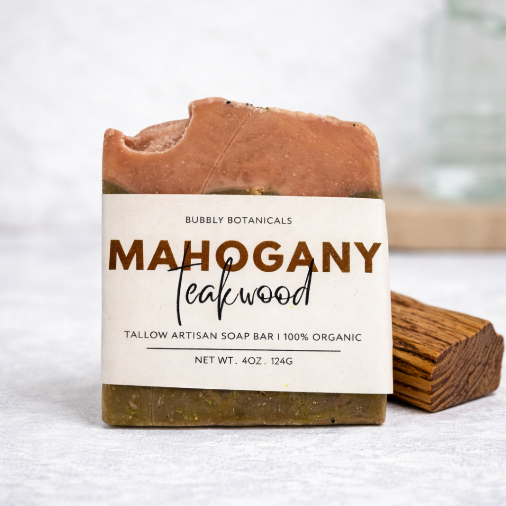 Bar of grass-fed tallow soap with a label indicating 'Mahogany Teakwood' fragrance on a white background.