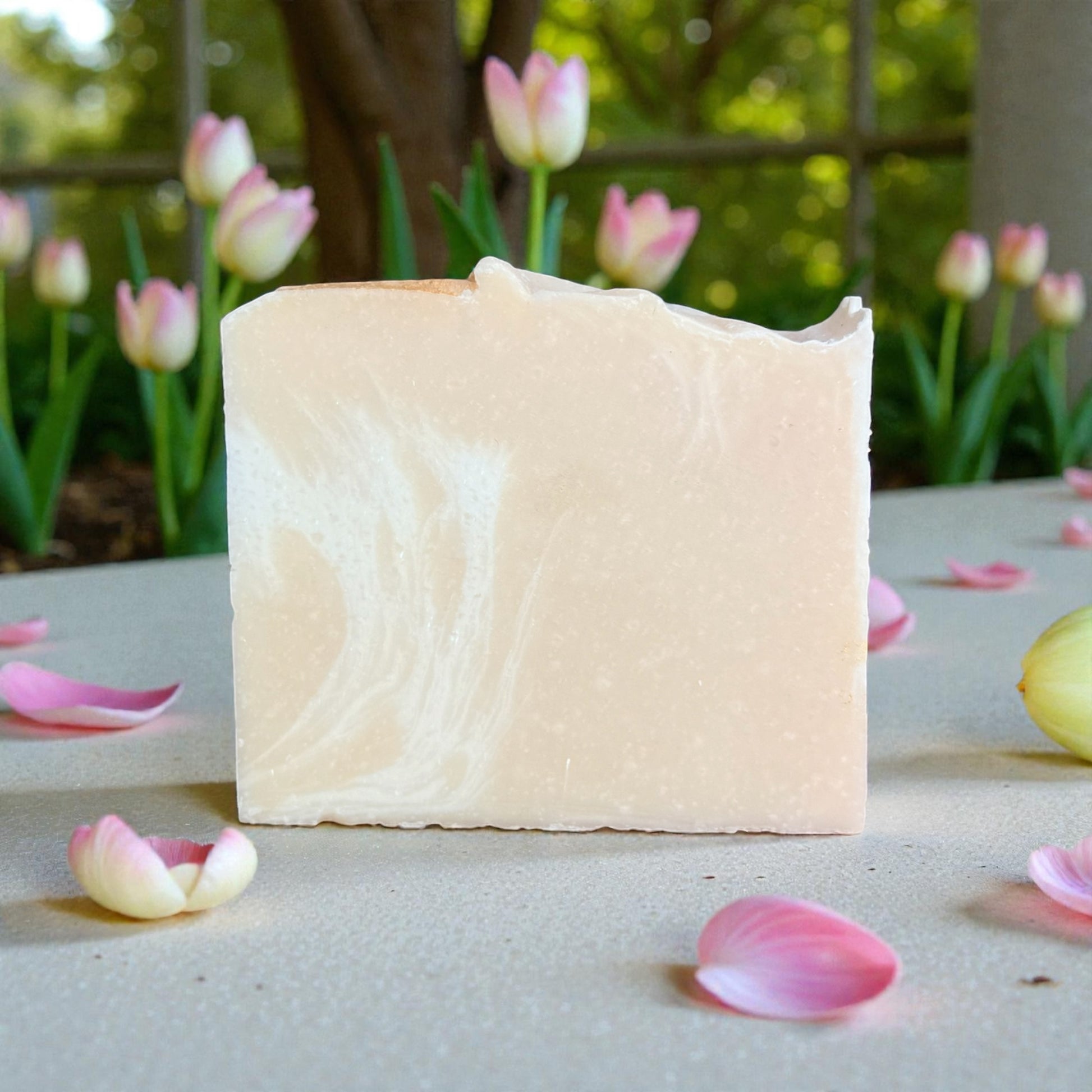 Bar of soft petal tallow soap with pink tulips and petals on a natural background