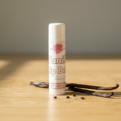 Vanilla lip balm with vanilla beans on a wooden surface