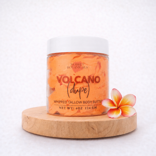 Jar of 'Volcano' tallow body butter on a wooden platform with a flower on a white background