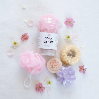 Soap gift set with bath pouf, soap bars, and flowers on a white background