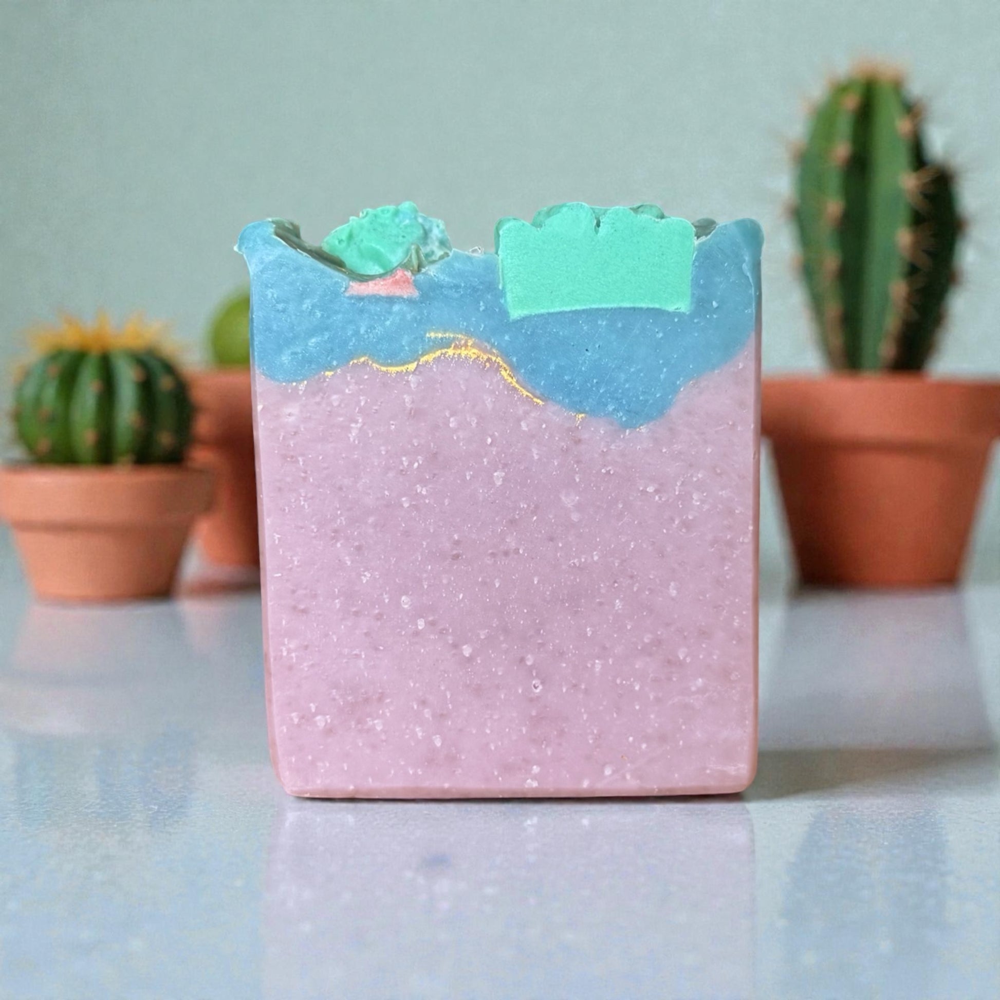 Bar of cactus blossom tallow soap with a mountain design on a reflective surface with cacti in the background