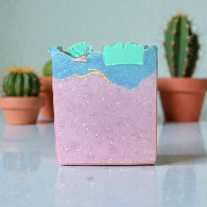 Bar of cactus blossom tallow soap with a mountain design on a reflective surface with cacti in the background