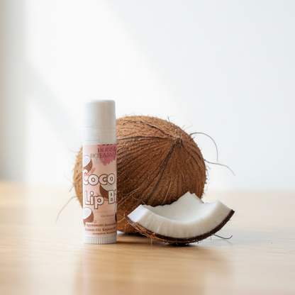 Coconut and a tube of lip balm on a wooden surface with a blurred background