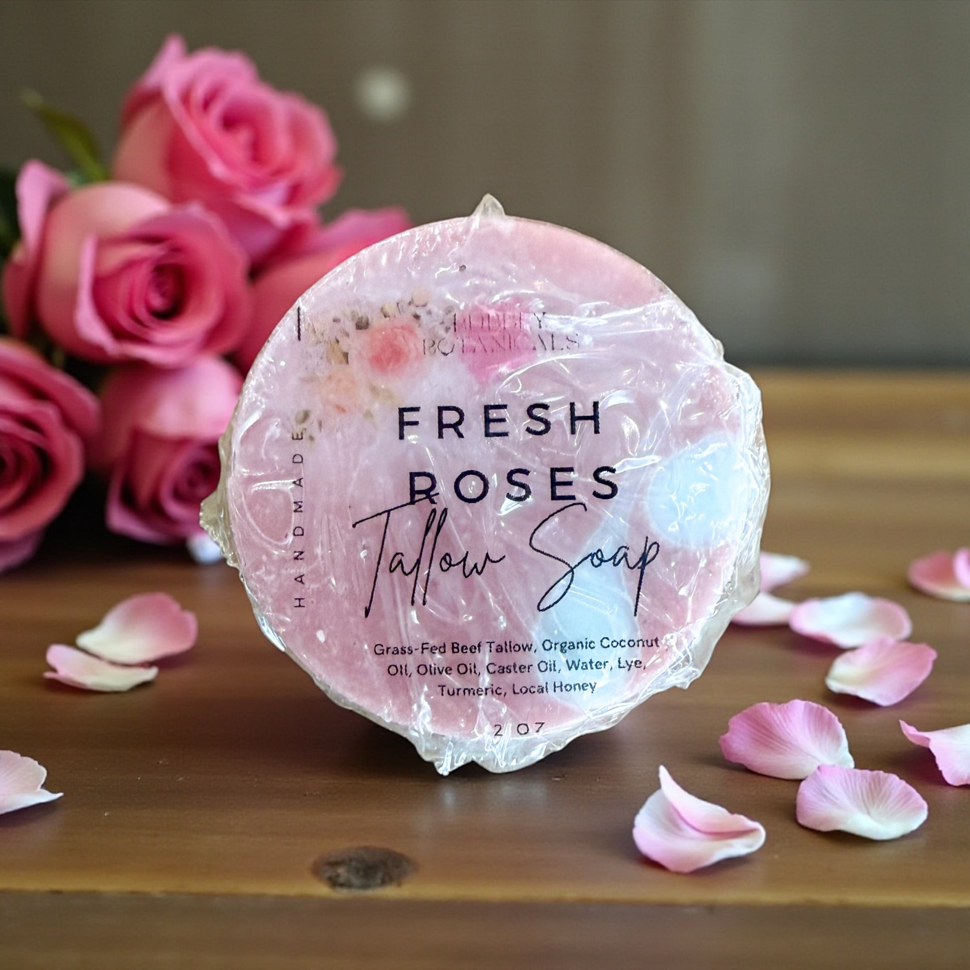 Pink tallow soap bar labeled 'Fresh Roses' with pink roses and petals in the background.